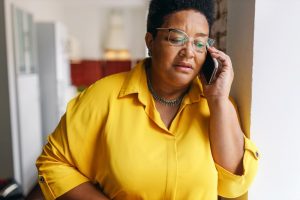 Woman with somber expression talking on the phone.