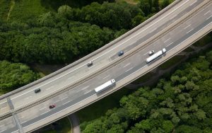Skyview of highway with vehicles, surrounded by trees.