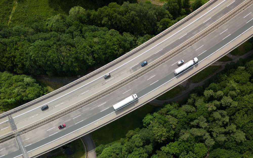 Overhead view of highway with vehicles, surrounded by trees.