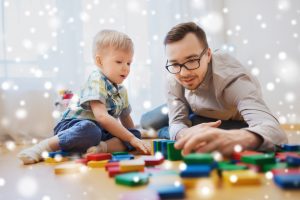 Father and young son sitting on floor and playing with blocks