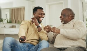 Father and son sitting on couch and laughing together, completely at peace