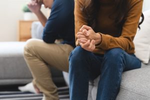 Two family members sitting on a couch facing away from each other in a disagreement