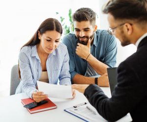 Couple sitting at table with advisor in suit as they look at documents together