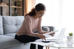 Young woman in pink sweater and glasses sitting at home and going over her estate plan