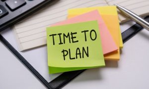 Post-it note that says "Time to Plan" sitting on a desk