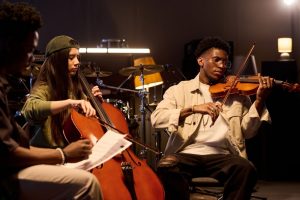 Woman playing a cello, seated by man playing a violin.