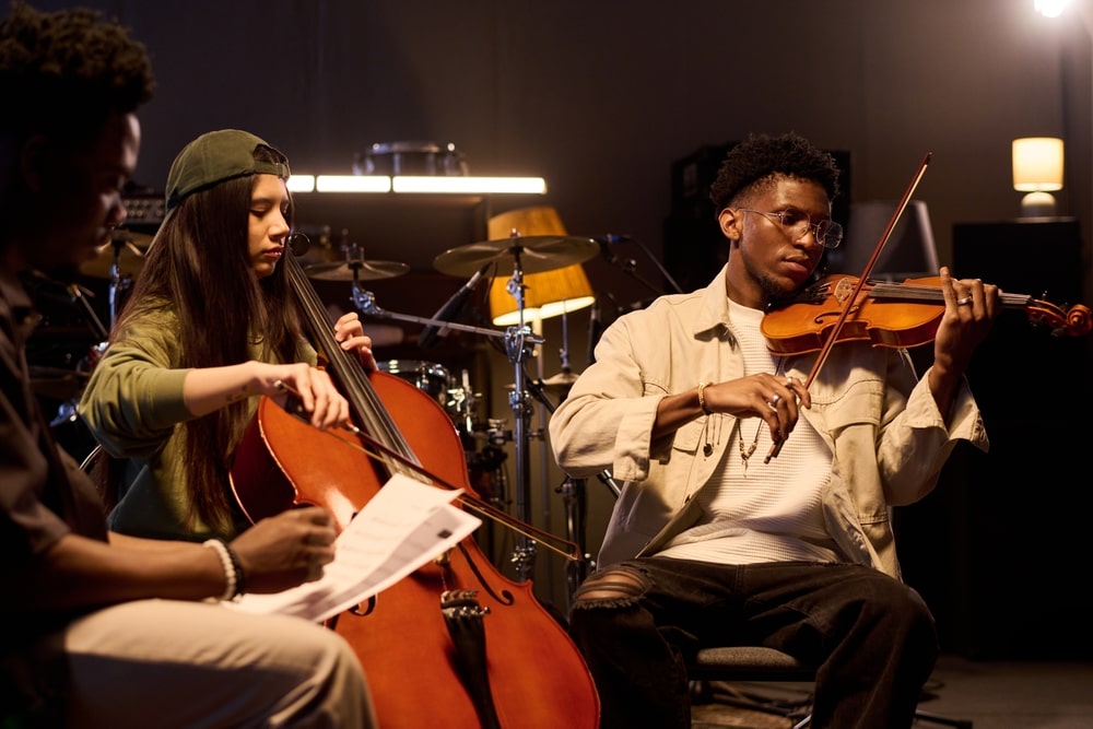 Woman playing a cello, seated by man playing a violin.