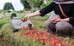 A woman sprinkles flower petals on a loved one's grave