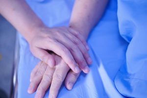 hand on top of another hand on a bed