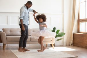 Father and young daughter dancing at home