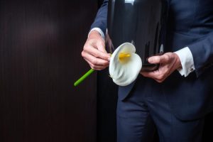 Man in suit holding an urn and a white lily