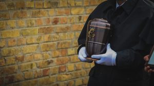 A decoratively detailed urn being carried reverently