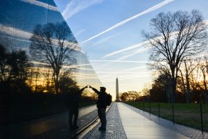 Man standing at Vietnam Memorial and honoring those who gave their lives for our nation