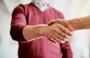 Man in red sweater shaking hands with another man