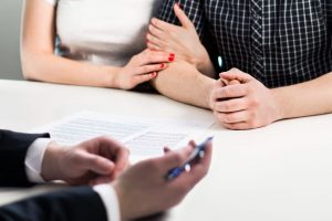 Celebrant reviewing written eulogy with grieving couple