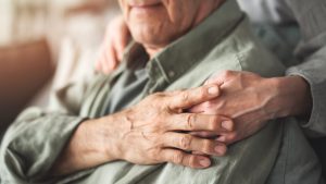 Close up of a man's shoulder with him holding hands with someone standing behind him.