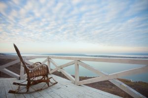 empty rocking chair on a deck looking out towards the water