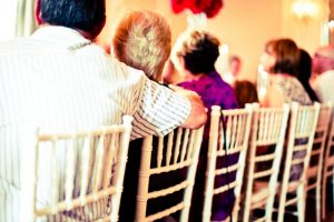 The back of people's heads, sitting in chairs at an event