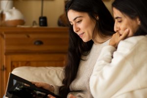 older mother and daughter looking at a photo album at home