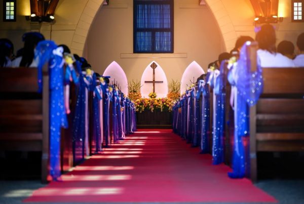 The inside of a church with bright blue ribbons tied to the pews, a cross on display at the front
