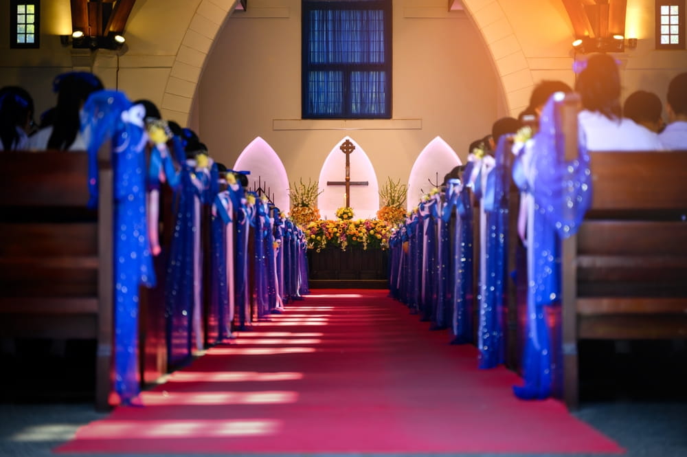 The inside of a church with bright blue ribbons tied to the pews, a cross on display at the front