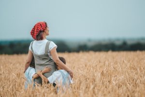 mom and two kids standing in a field and gazing out to the trees