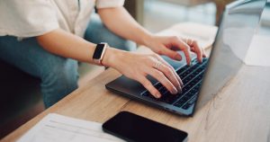 Woman typing on a computer while sitting on a couch