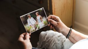 Woman holding a color photograph of a man and woman