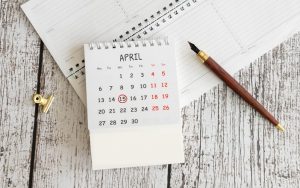 A clip, pen, and calendar with the 15th of April circled, all lying flat on a table