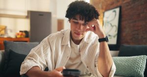 Man sitting on a couch looking at his phone