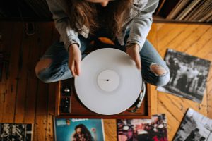 woman holding a white vinyl record while sitting on the floor