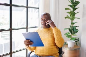 A man on the phone looking at a clipboard