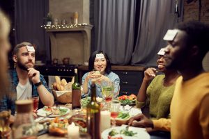 multicultural friends playing a game together at the dinner table