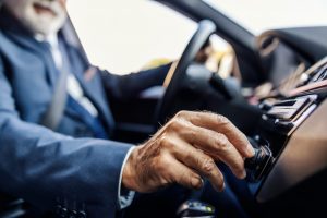 Close up of a man in a car adjusting the control knobs. 