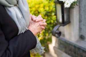 Close up of someone's clasped hands standing by a permanent memorial.