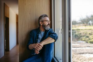 man sitting alone, looking out a window