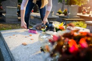 Woman cleaning a grave by sweeping away leaves
