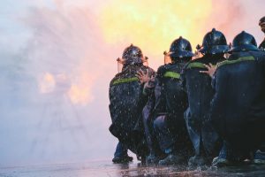 Firefighters crouching down in front of fire.