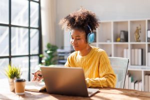 A girl with headphones on looking at her computer