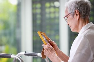 Woman holding a photo and gazing somberly.