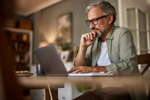 An older man looking thoughtfully at his computer