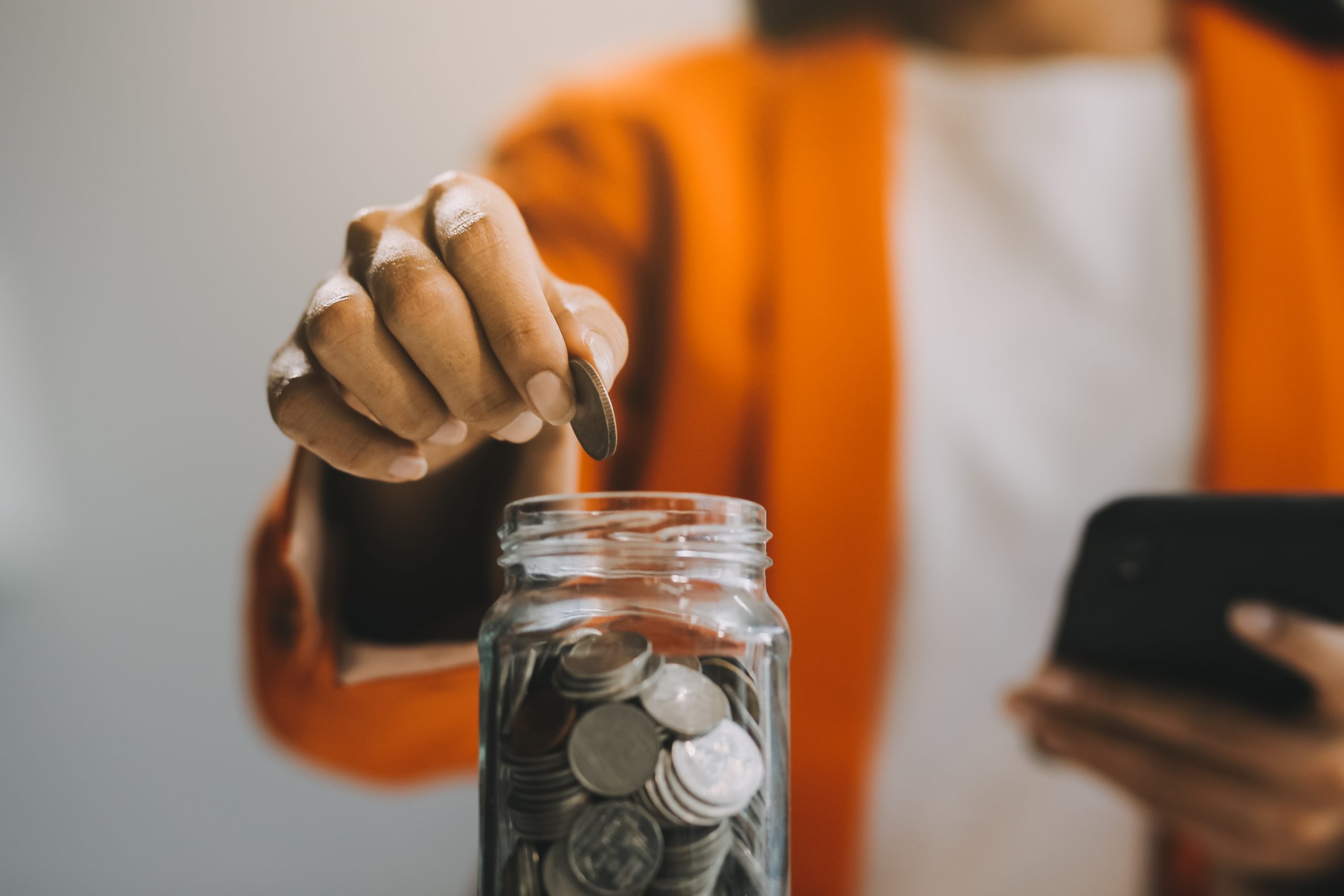 A person adding money to a coin jar