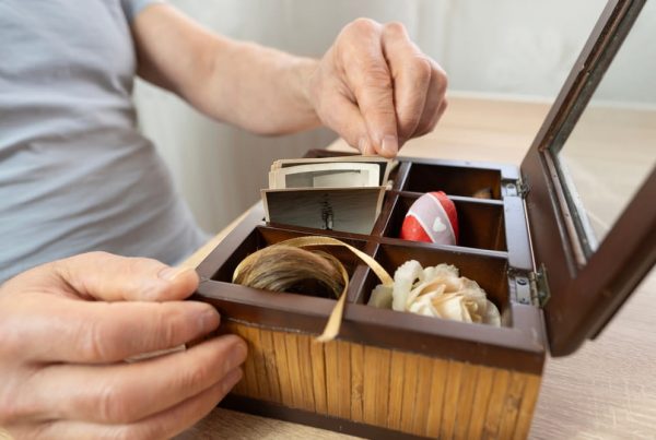 A man pulling things out of a wooden keepsake box.