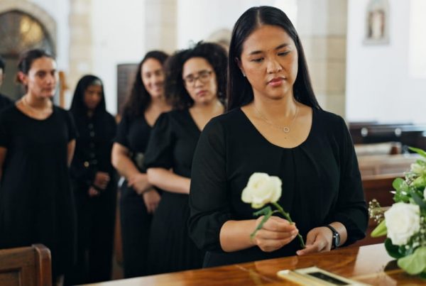 People dressed in black, standing in line by a casket.