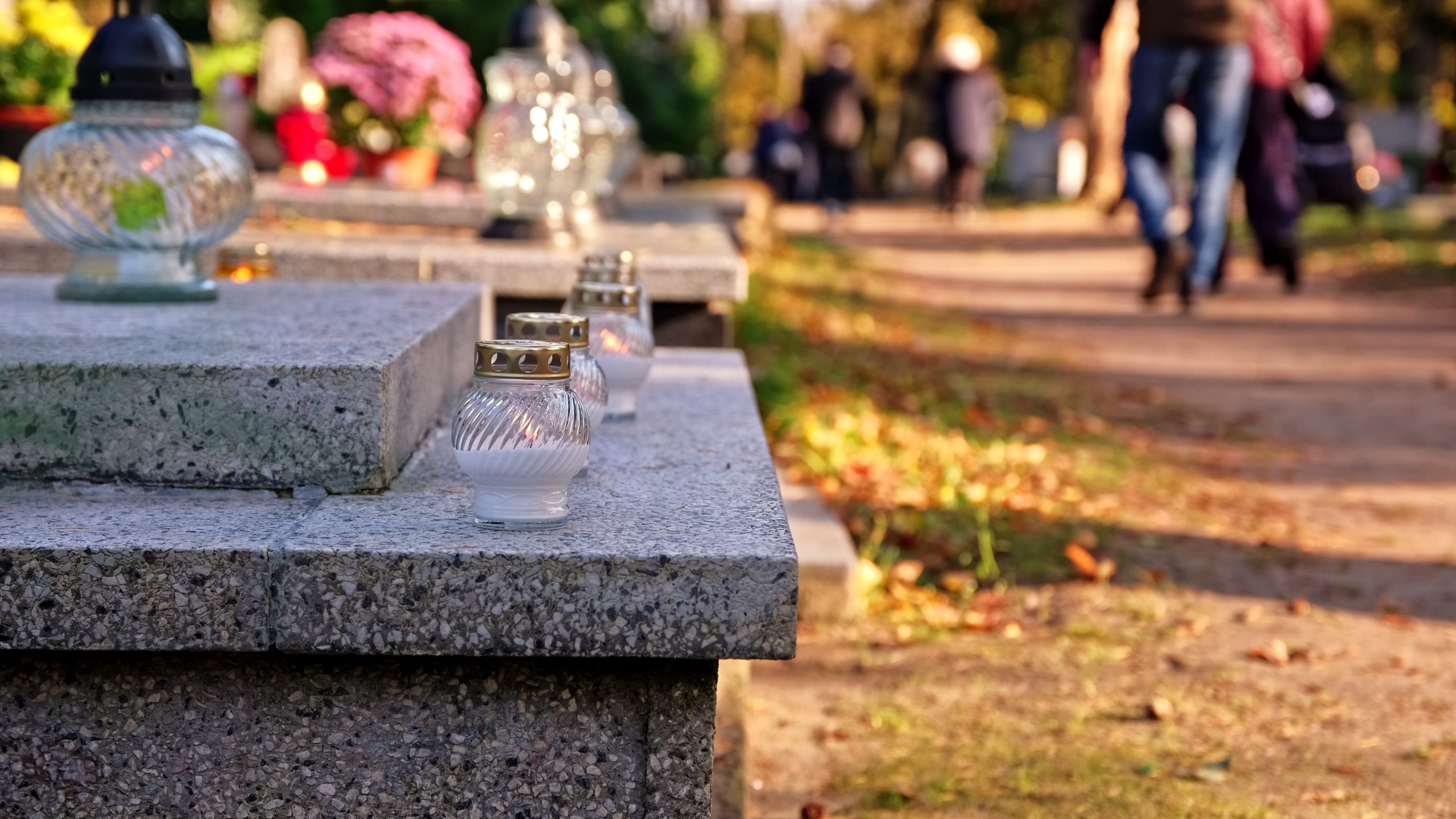 lanterns placed on a headstone and people walking in the background