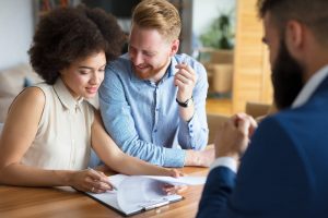 Young couple speaking with estate planning attorney and signing official documents