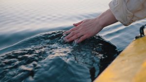 Person skimming their hand across the surface of the water