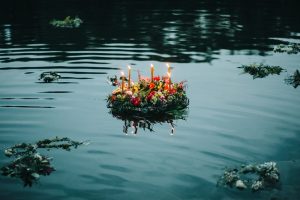 Wreath of flowers and candles floating on the surface of a lake