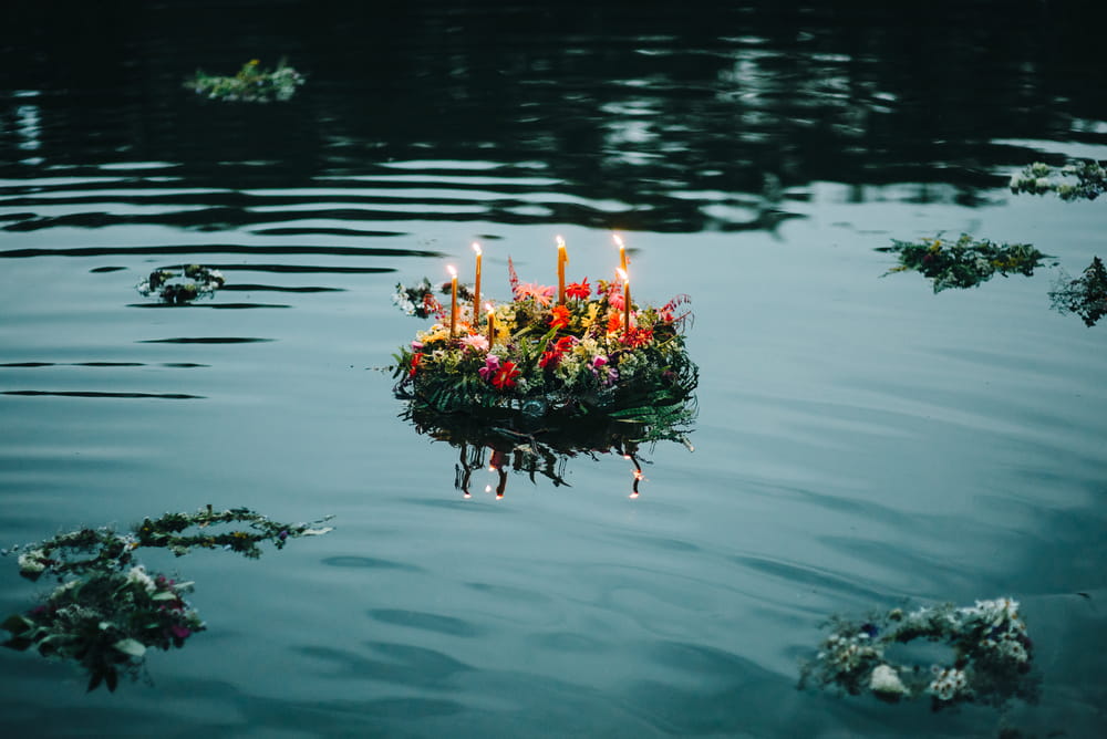 Wreath of flowers and candles floating on the surface of a lake